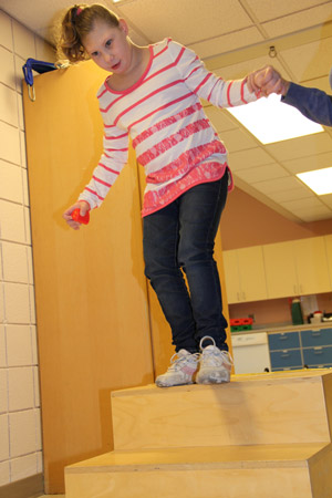 Braelynn practices climbing stairs during her session with Physical Therapist Cheryl Jabara