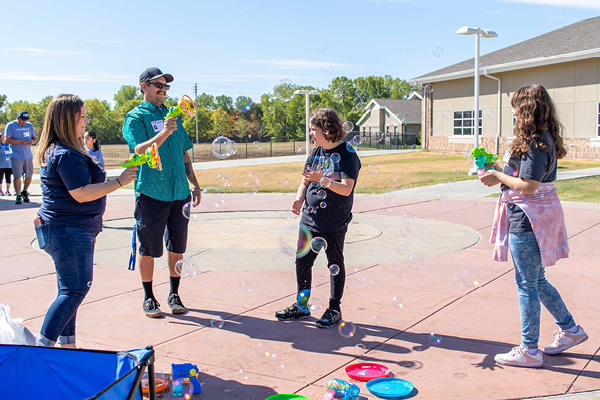 Heartspring student and her family playing with bubbles during Family Weekend in the school courtyard