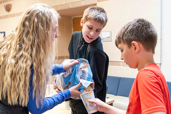 CARE Coordinator and two clients pouring flour into a cup for an activity