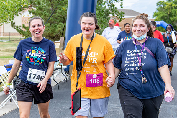 Heartspring direct support professionals and a student walking and smiling
