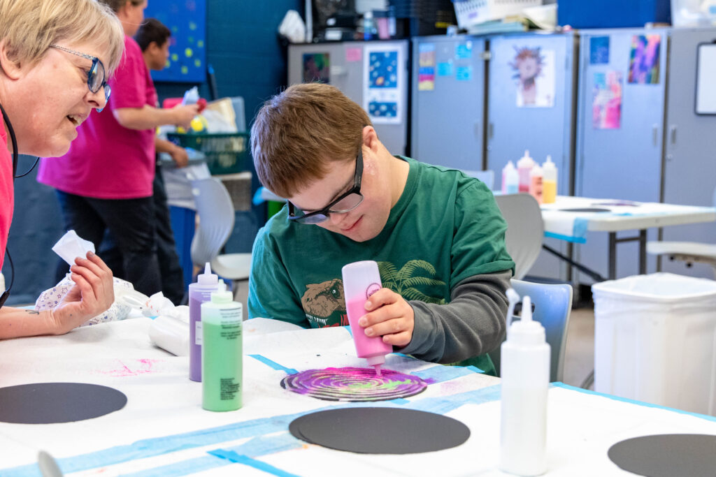 Heartspring student sitting at a table working on a sand art project