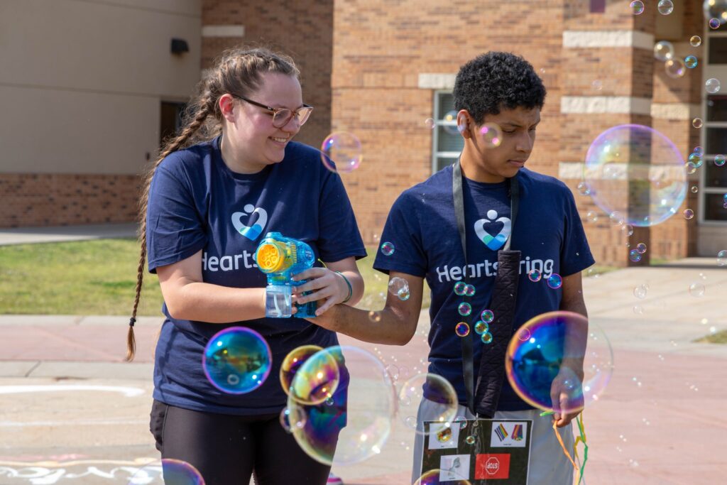 Heartspring direct support professional and student playing with a bubble toy at Family Weekend
