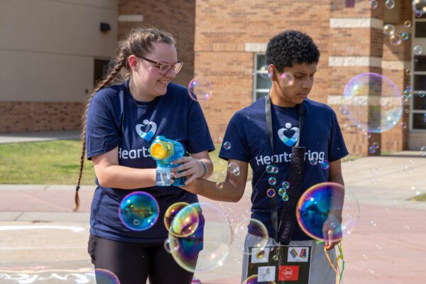 Heartspring direct support professional and student playing with a bubble toy at Family Weekend