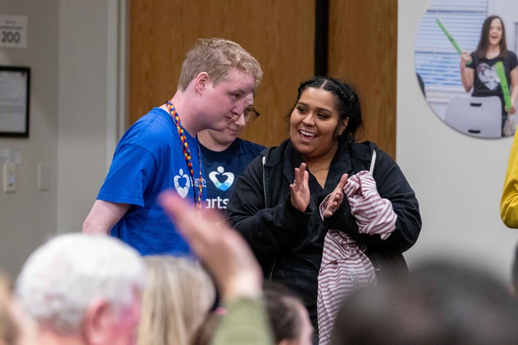 Heartspring direct support professional claps along side a student during the Family Weekend music performance