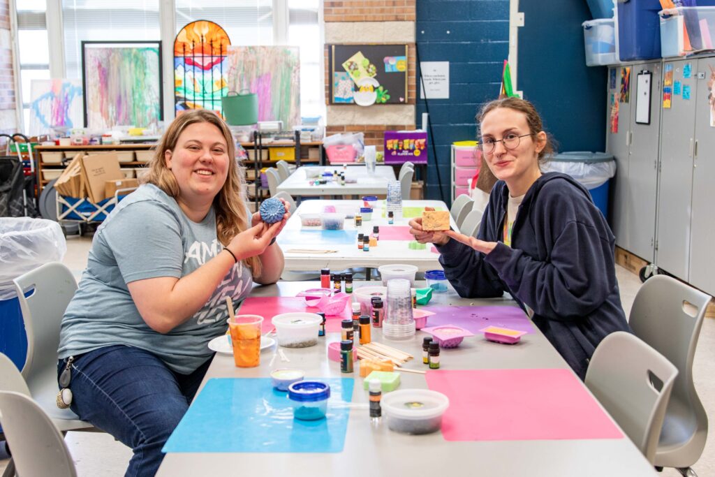 Two Heartspring employees holding up the soap they made at an employee art day