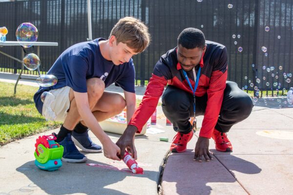 Heartspring direct support professional and student working together to paint with sidewalk paint