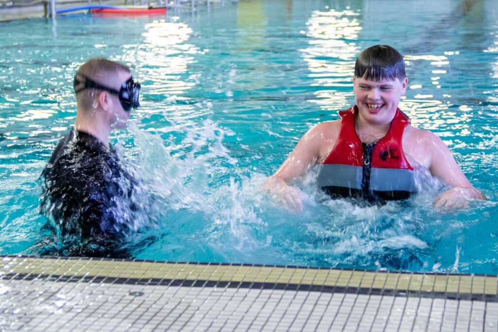 Heartspring Adapted Physical Education teacher and student swimming in the Heskett Center swimming pool