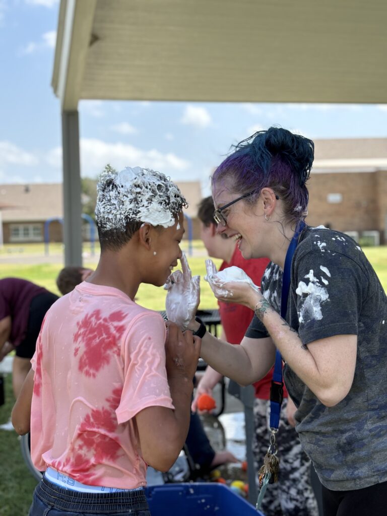 Heartspring direct support professional and student play with shaving cream during a Sunday Funday event