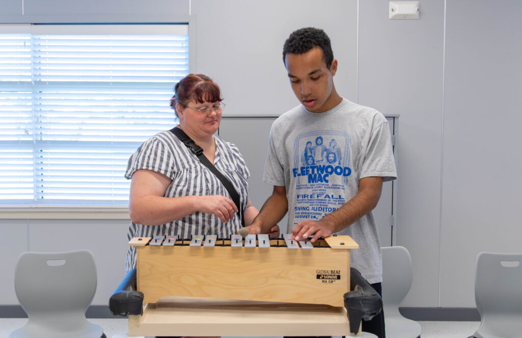Heartspring direct support professional and student playing a xylophone in music class