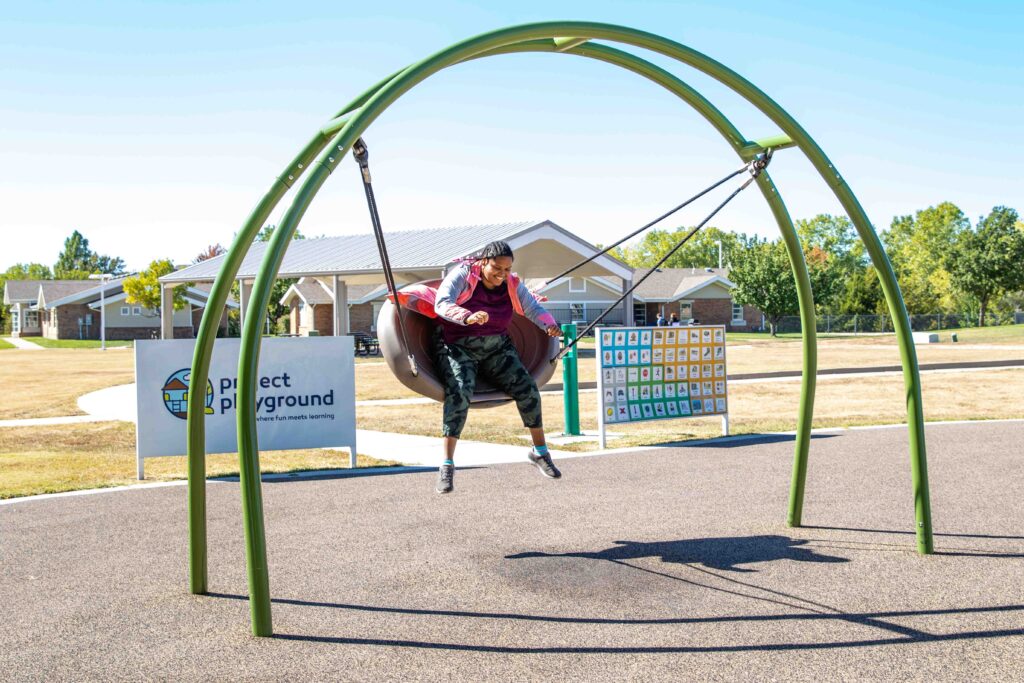 Heartspring student swinging on a swing in the adaptive playground on campus