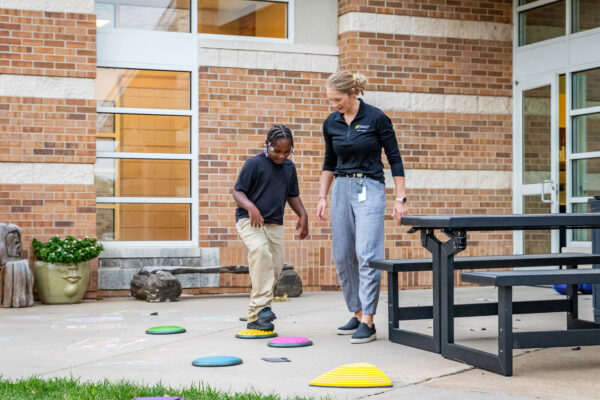 Pediatric physical therapist working with a client on gross motor skills using stepping stones