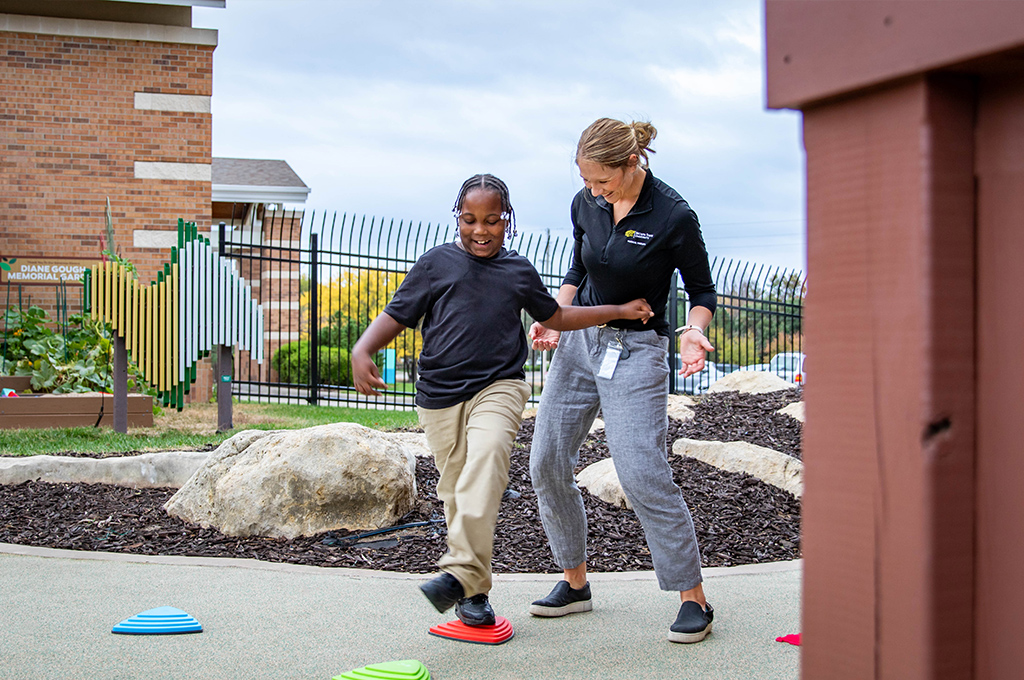 Pediatric physical therapist working with a client on gross motor skills using stepping stones