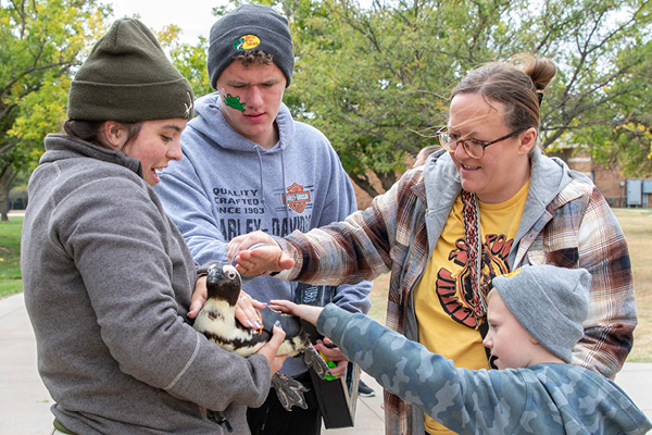 Heartspring student and his family petting a Tanganyika Wildlife Park penguin during Family Weekend