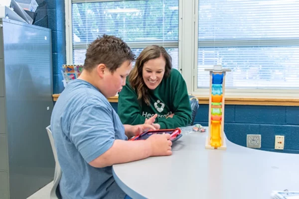 Heartspring student working with a speech-language therapist on an iPad communication device