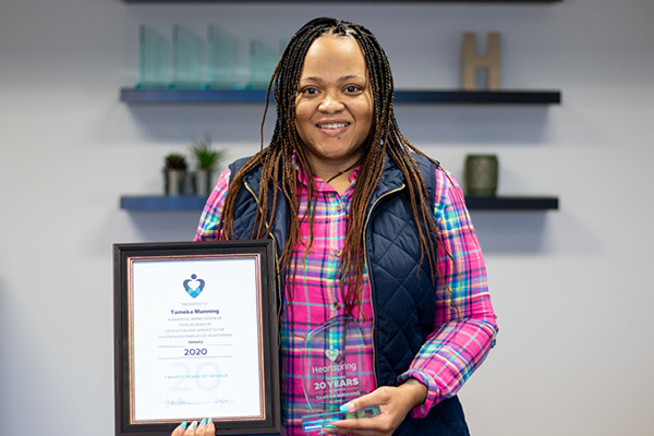 Heartspring employee holding a certificate and trophy celebrating 20 years of service