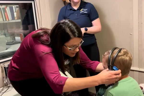 Heartspring audiologist adjusts headphones on a client in a pediatric audiology session