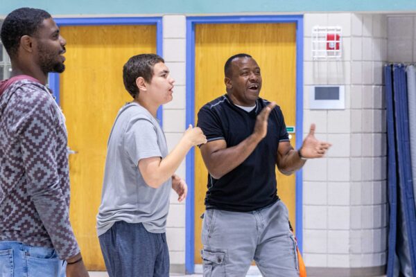 Heartspring direct support professional and student standing in the school gym