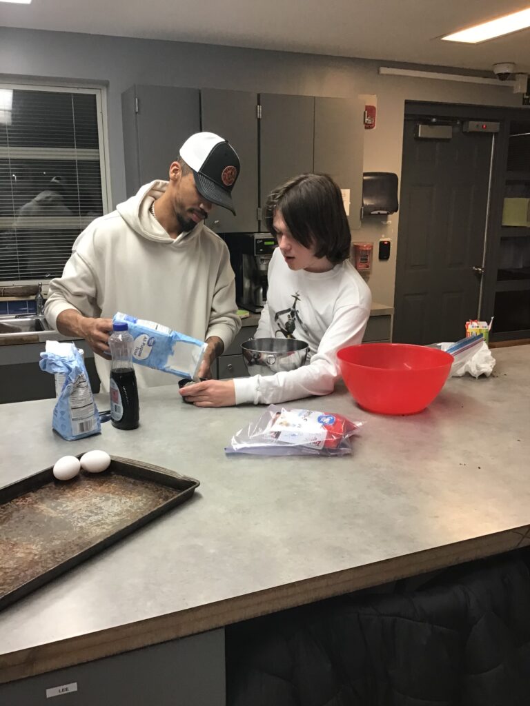 Heartspring direct support professional and student baking cookies in a residential group home