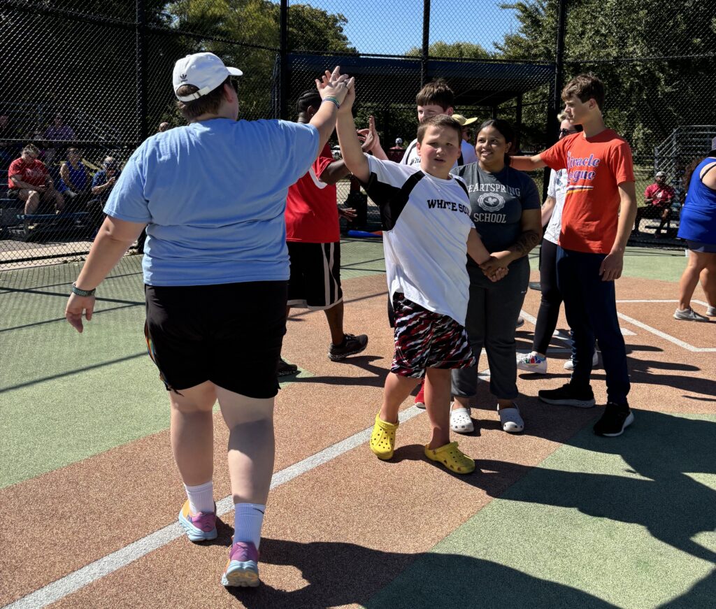 Heartspring student high-fiving a staff member after a Miracle League baseball game
