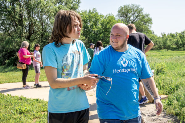 Heartspring therapeutic school special education teacher holding hands and walking alongside a student at Sedgwick County Park
