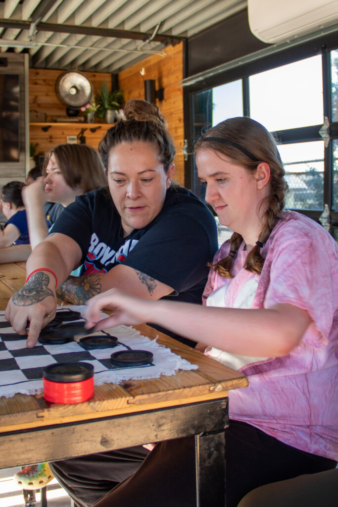 Heartspring direct support professional and student playing checkers at Chicken N Pickle during a community outing