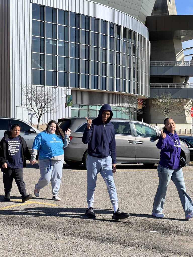 Heartspring direct support professionals and students walking in a line and waving at the camera in front of INTRUST Bank Arena in downtown Wichita