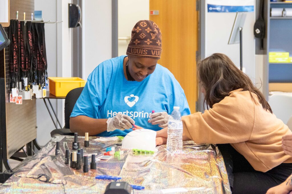 Heartspring direct support professional painting a student's fingernails during a Girls Group activity