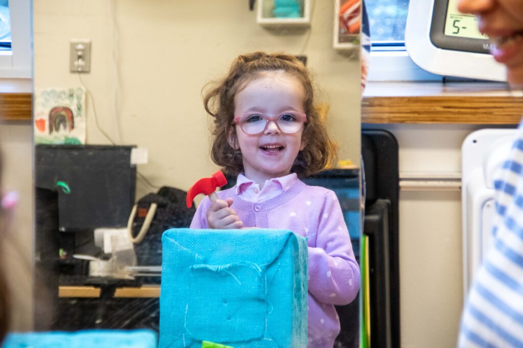 Young child looking at the camera and smiling in a pediatric occupational therapy early intervention session