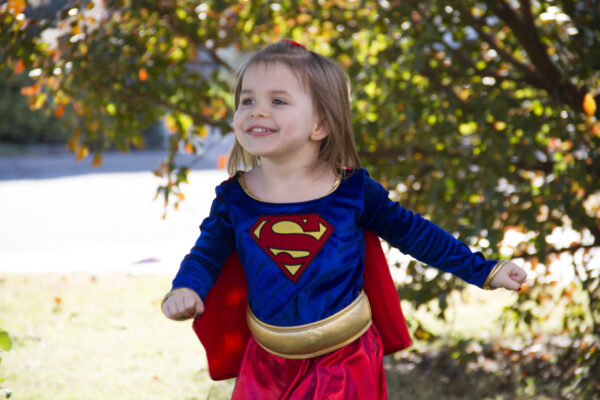 Heartspring pediatric clinic client Abigail smiling while wearing a Superwoman costume