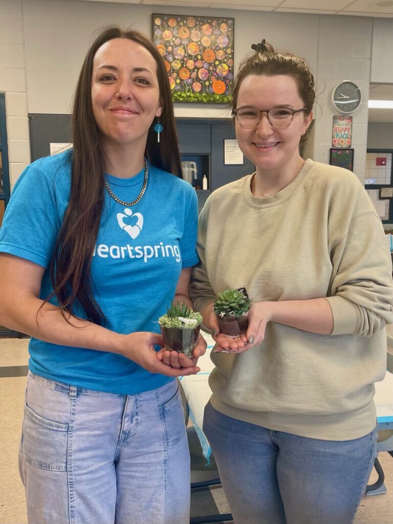 Heartspring employees holding succulent containers they designed during an employee art day