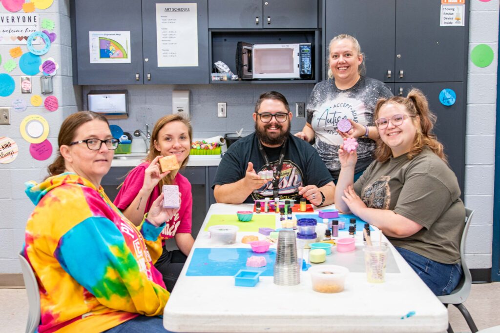 Group of Heartspring employees hold up soap they made during an employee art day