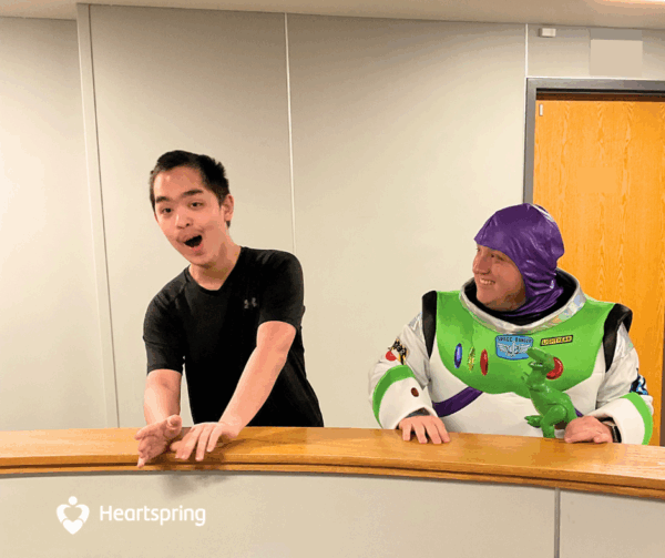 Heartspring special education teacher dressed as Buzz Lightyear and holding a T-Rex, stands next to excited Heartspring Therapeutic Residential School student.