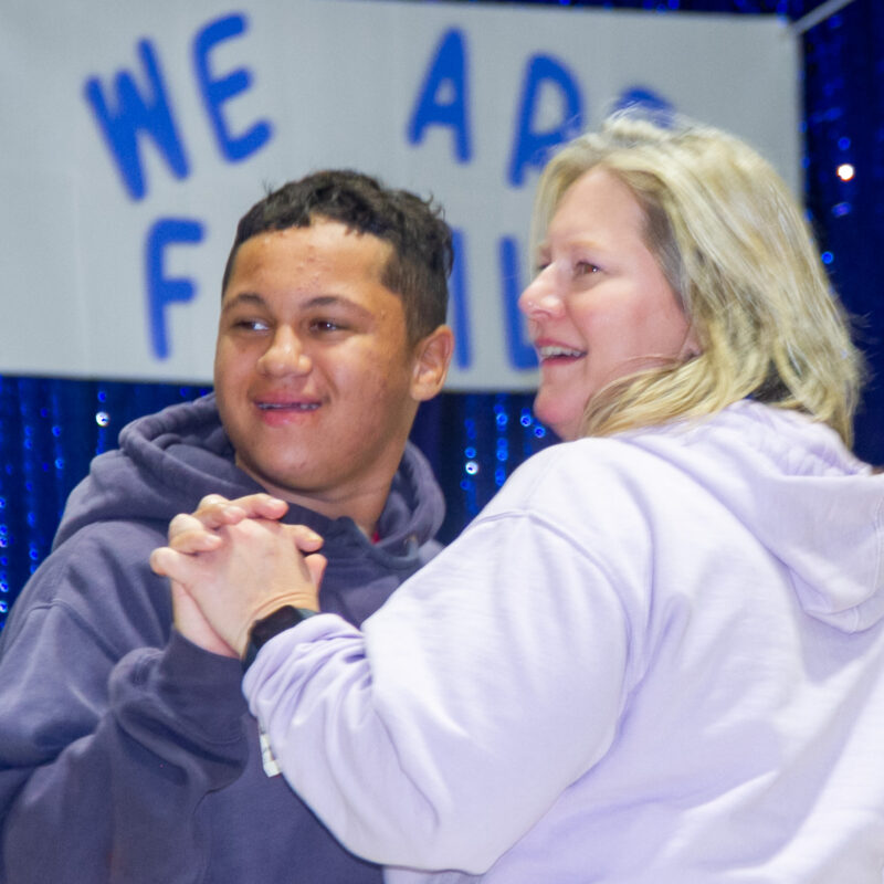 Heartspring student and his mom holding hands, smiling, and dancing at the Family Weekend dance