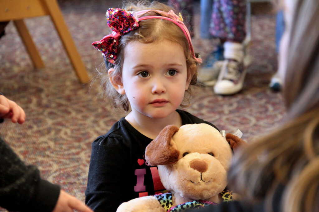 Heartspring pediatric clinic client Holly holding a stuffed teddy bear during a pediatric speech-language therapy session