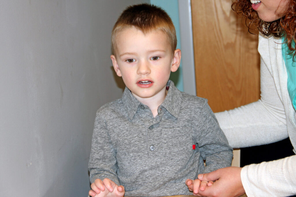 Sawyer sitting at a table during a pediatric speech-language therapy session