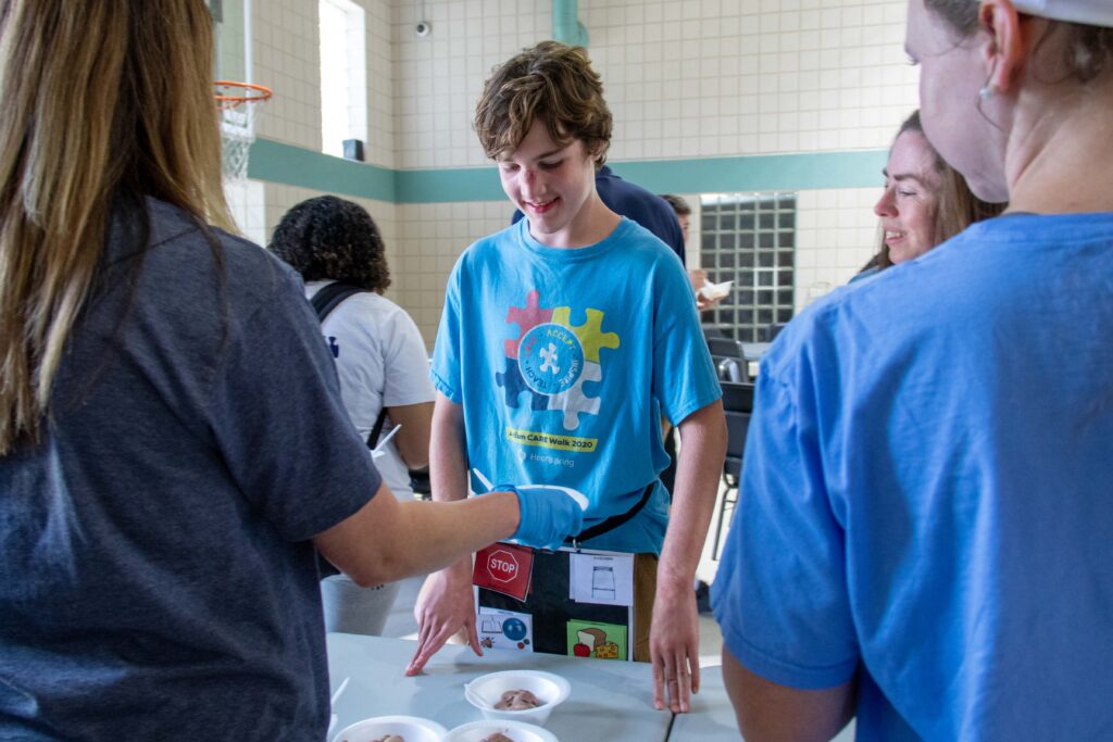 Heartspring Therapeutic School SLPs help student use a visual menu at an ice cream social.