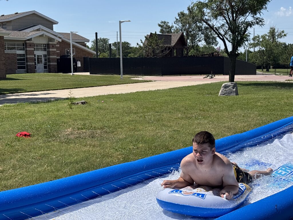 Heartspring Therapeutic Residential & Day School student enjoys the slip and slide at Family Field Day.