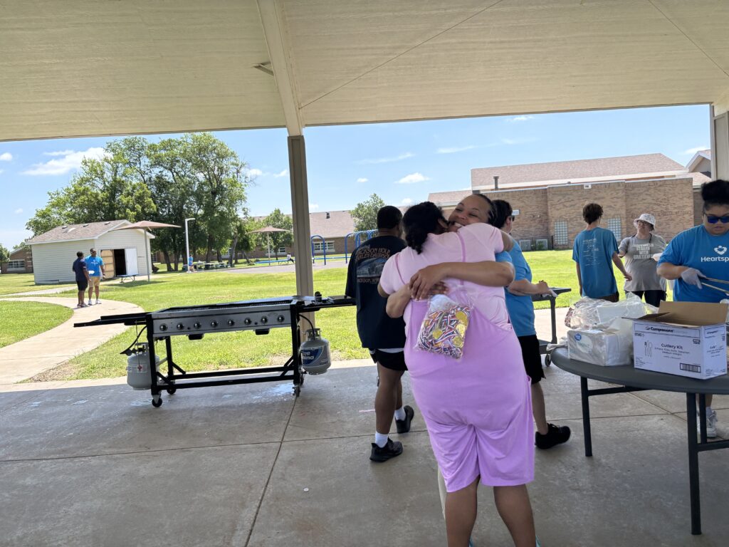 Lysh Dean, G4 supervisor and Values Ambassador, hugs a Heartspring Therapeutic Residential & Day School student while holding a bag of medals at Family Field Day.