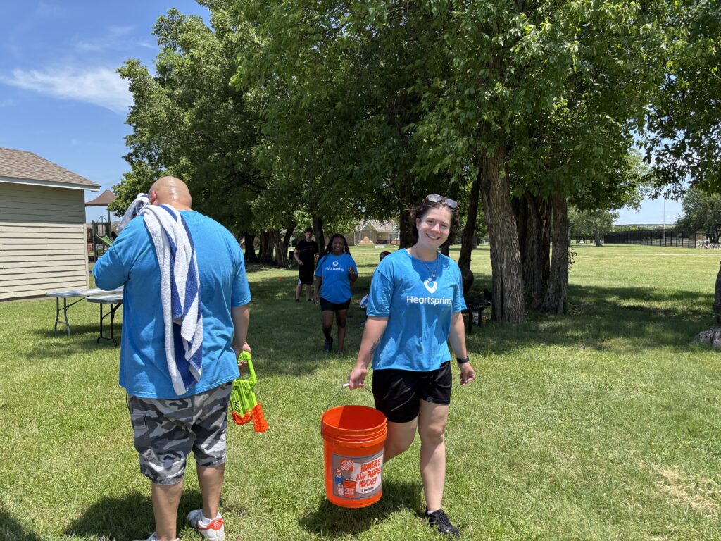 Heartspring Therapeutic Residential & Day School staff smiles as she carries a 5-gallon bucket of water at Family Field Day.
