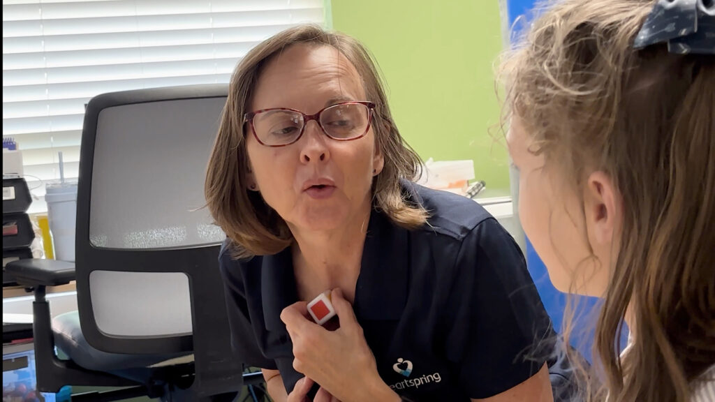 Rhonda Witherspoon, a speech-language pathologist in the Heartspring Pediatric Clinic helps model a word with a child.