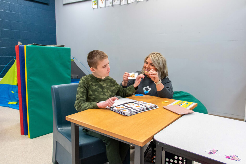Dr. Holli Matzen conducts a speech-language therapy session with a student in the Heartspring Therapeutic Residential & Day School using an AAC system.