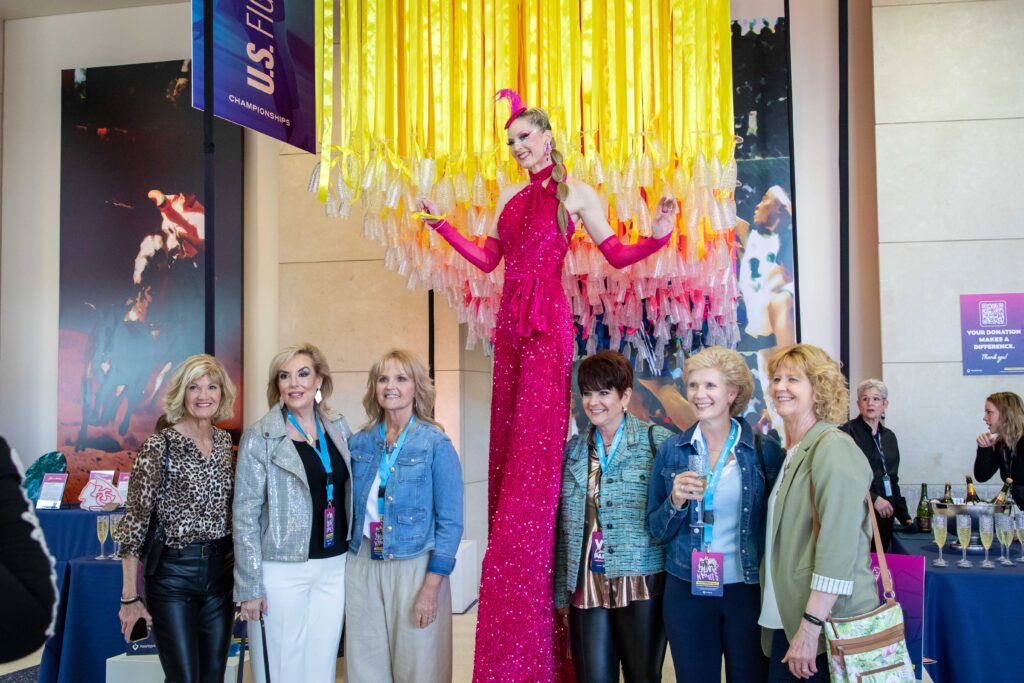 Heartspring Gala guests posing and smiling with a woman on stilts