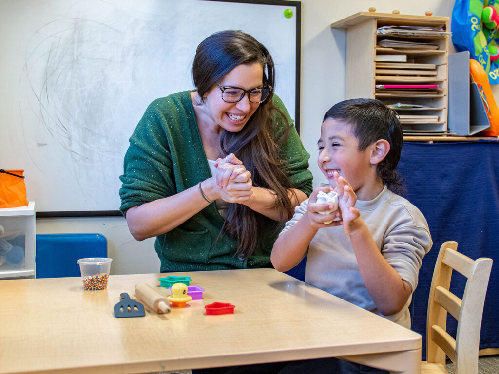 Heartspring occupational therapist working with a client on improving fine motor skills, hand strength, and dexterity by squeezing Play-Doh.