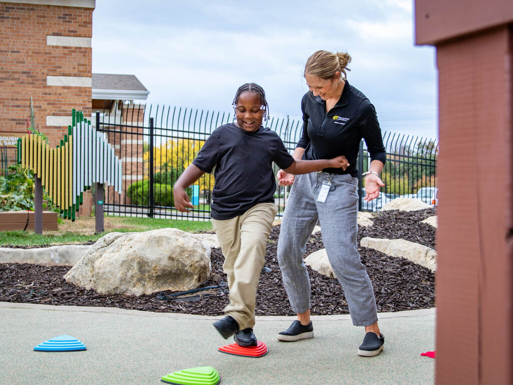 Pediatric physical therapist working with a client on gross motor skills using stepping stones