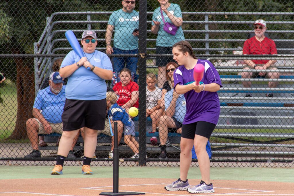 Heartspring student hits a wiffleball off a tee in a Miracle League game.