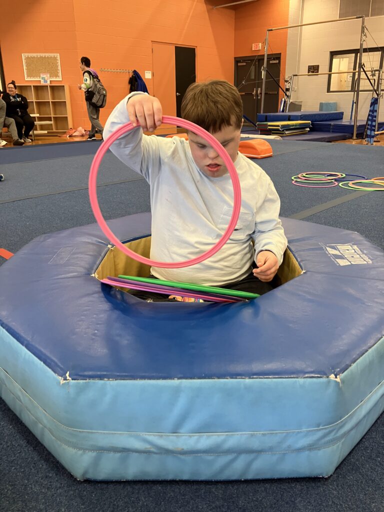 A student in the YMCA adaptive gymnastics class play with the differently-sized and colored rings.