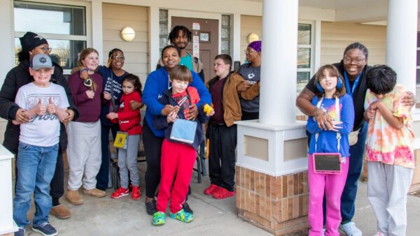 Values Ambassador Alyssa Tucker stands with her staff and students outside of their residential group home for a group picture.