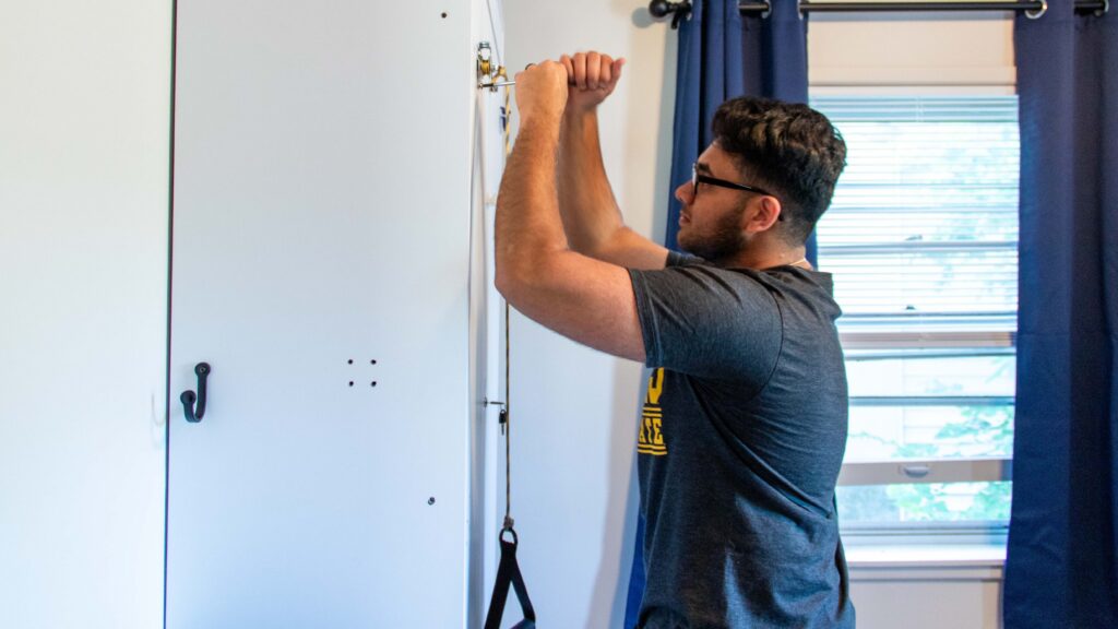 One of the three WSU engineering students working to create an adaptive Murphy bed solution for a Heartspring Pediatric Outpatient Clinic child, uses a screwdriver on a white door.