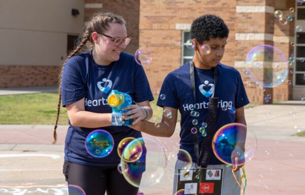Heartspring direct support professional and student playing with a bubble toy at Family Weekend.