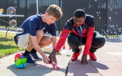 Heartspring direct support professional and student working together to paint with sidewalk paint.